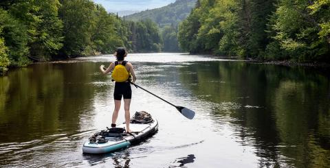 Personne qui fait de la planche a pagaie sur une riviere du quebec